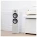 Monitor Audio Bronze 500 Floorstanding Speakers (Pair), White by a piano